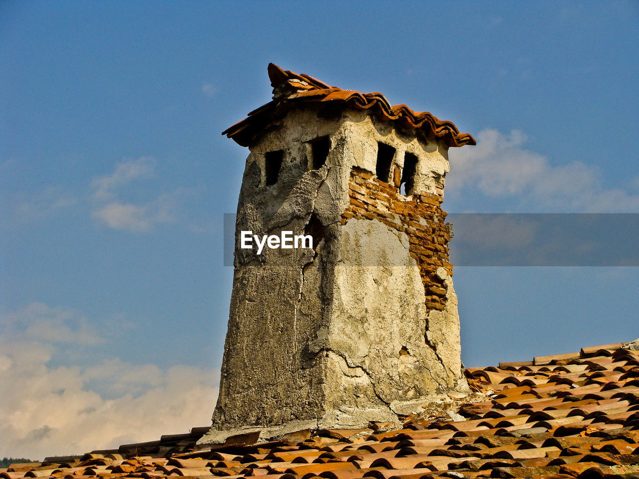 Damaged chimney against cloudy sky