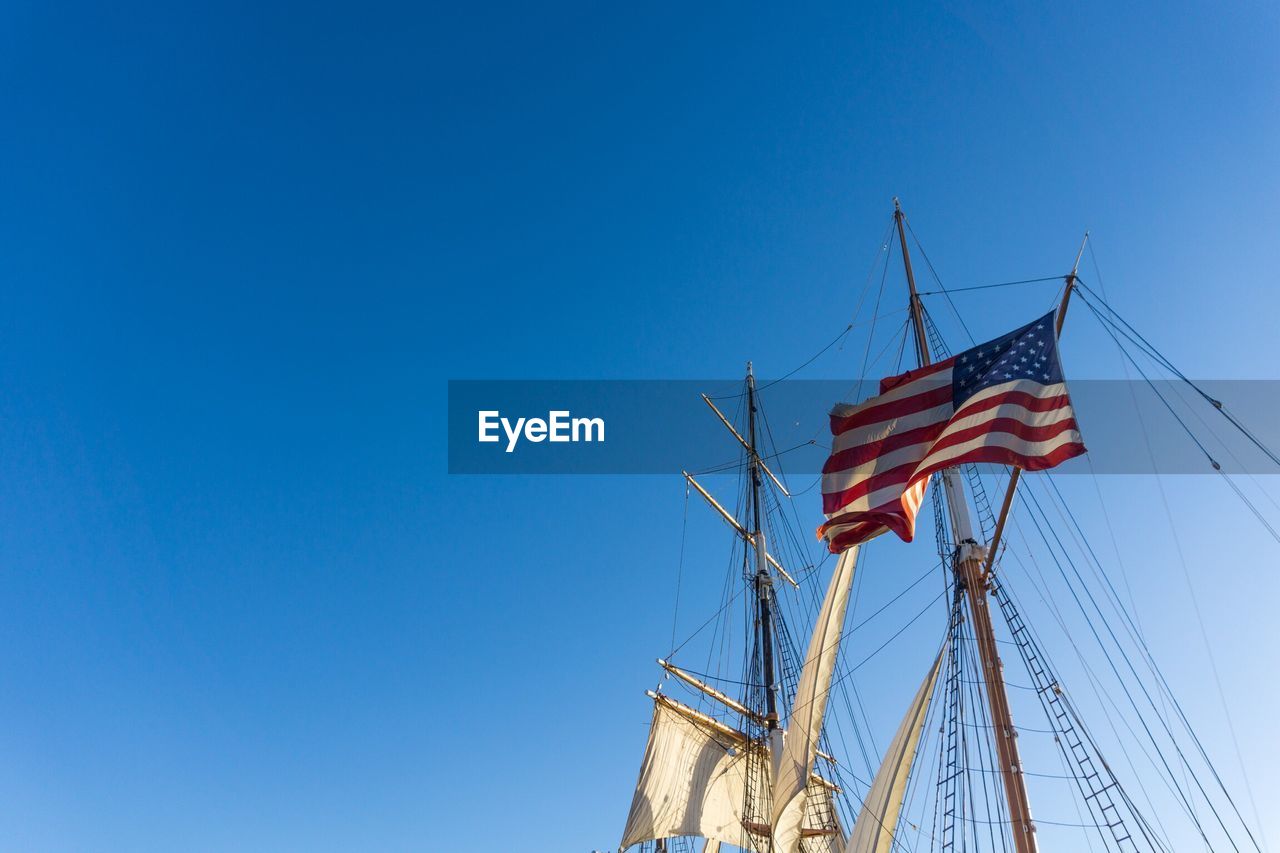 Low angle view of american flag on boat against clear blue sky