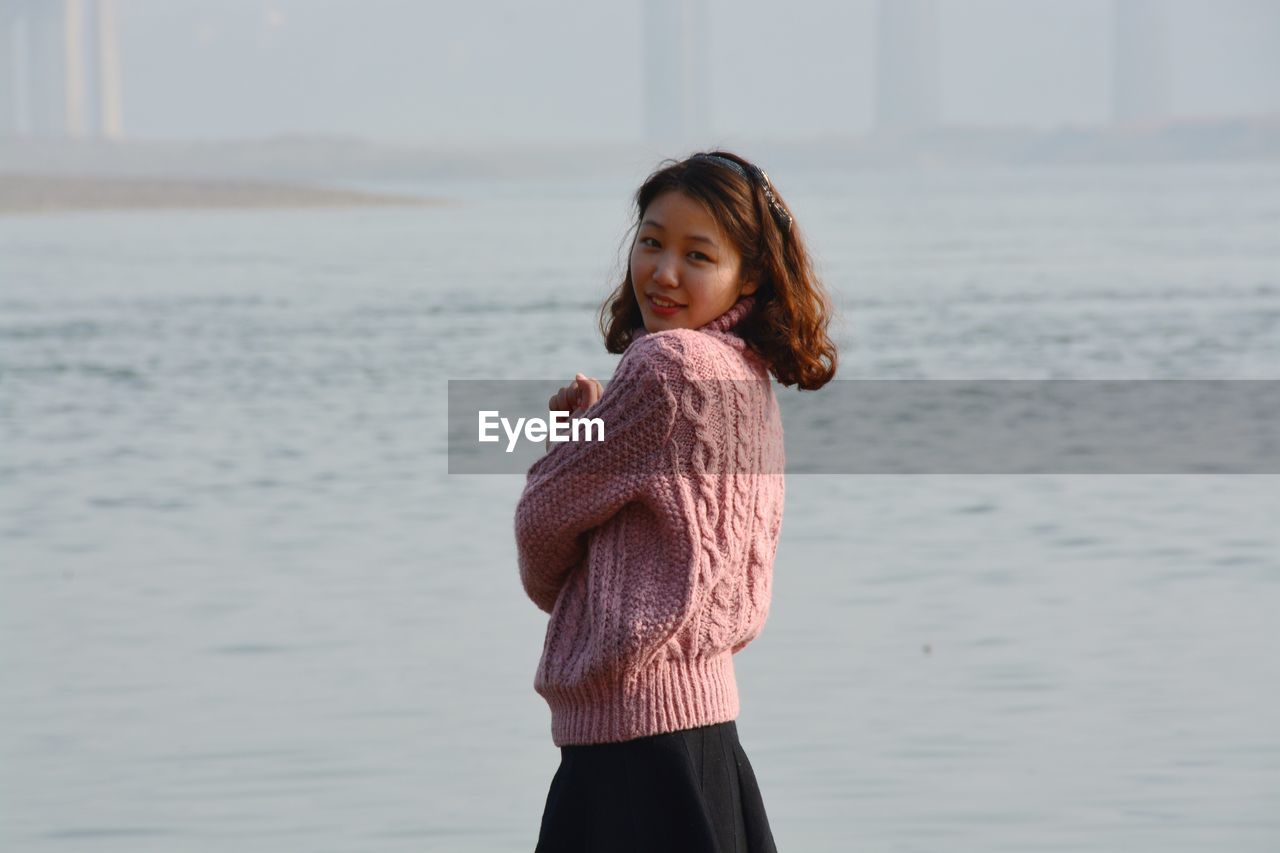 Portrait of smiling woman standing by sea