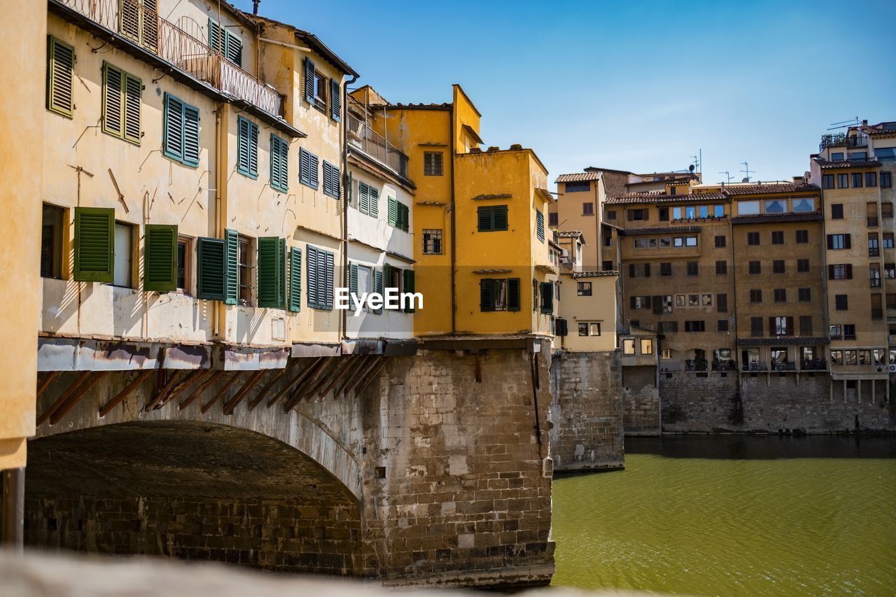 Arch bridge over river against buildings in city