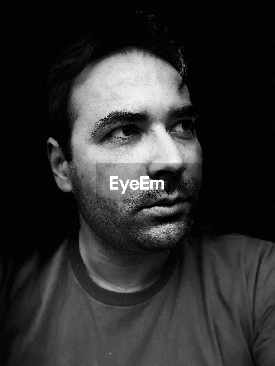 CLOSE-UP PORTRAIT OF YOUNG MAN AGAINST BLACK BACKGROUND