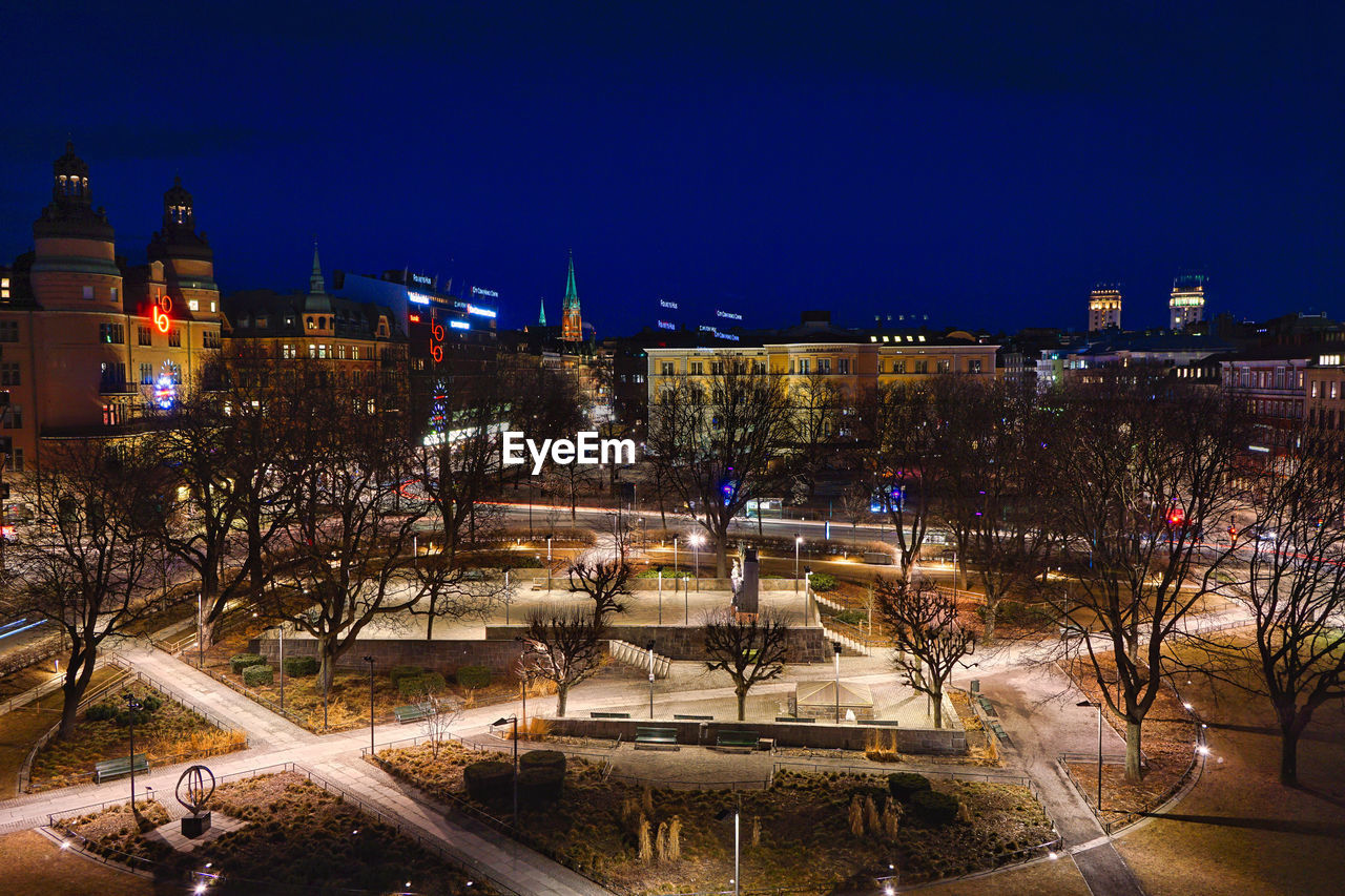 HIGH ANGLE VIEW OF ILLUMINATED CITY BUILDINGS AT NIGHT