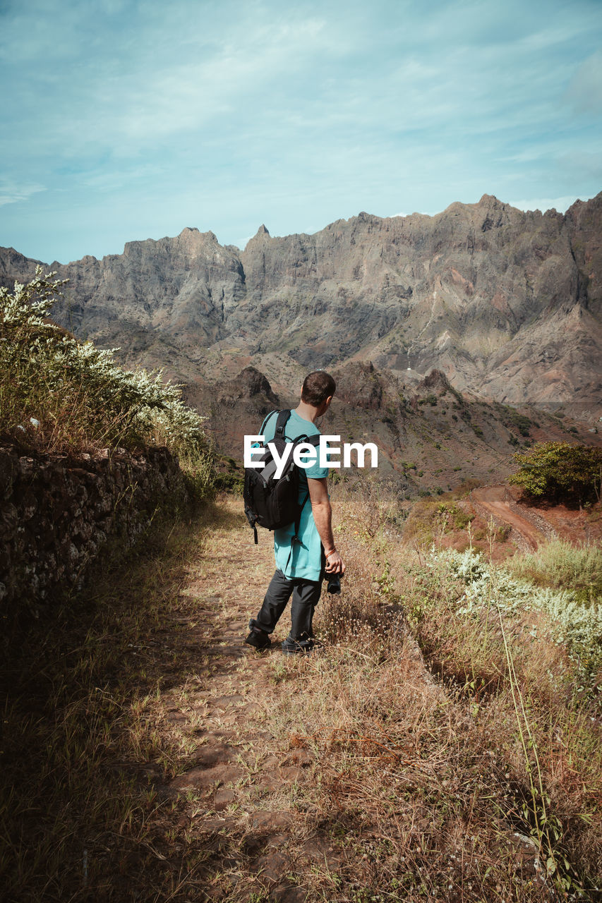 REAR VIEW OF FRIENDS WALKING ON MOUNTAIN