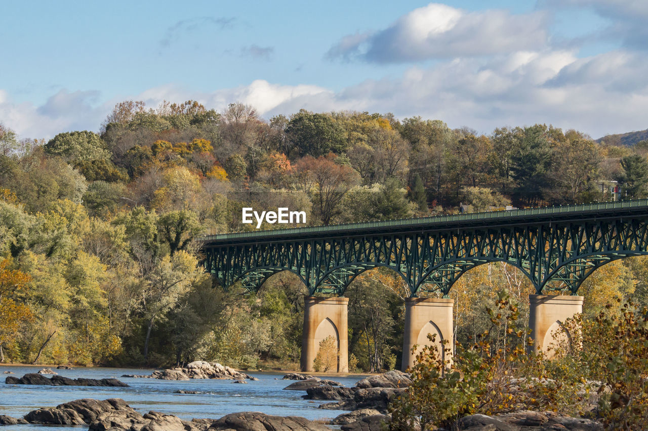 Bridge by trees against sky during autumn