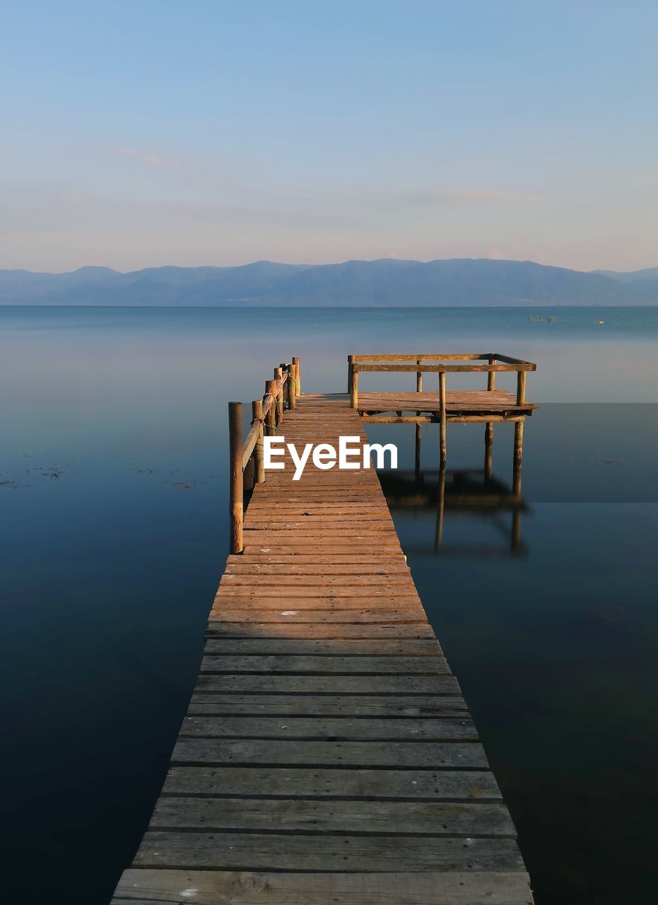 Wooden pier over lake against sky