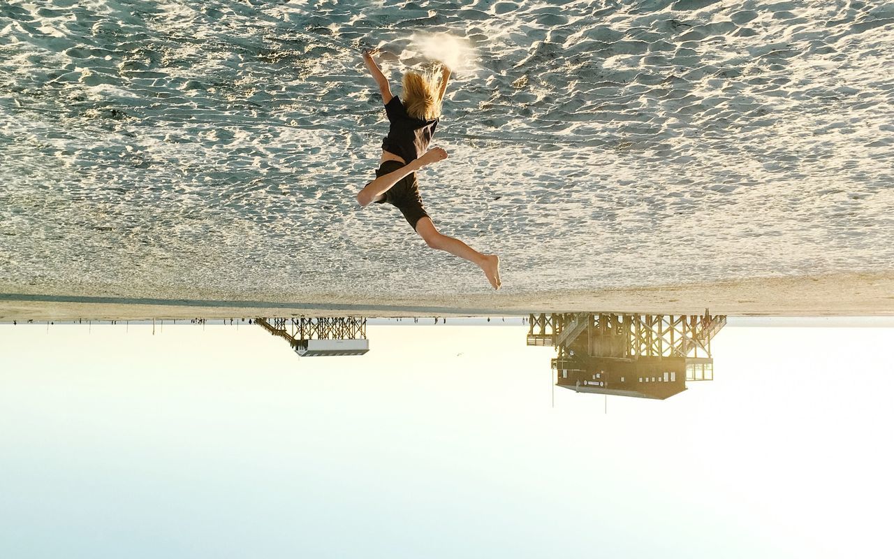Upside down image of boy jumping on sand at beach
