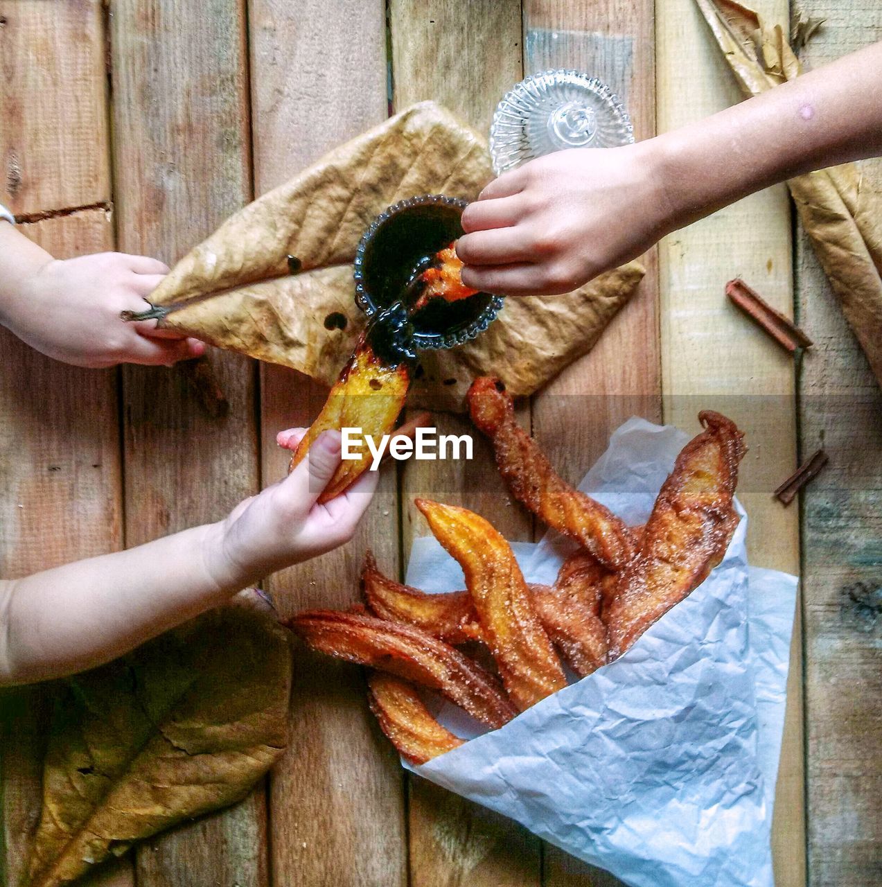 Cropped hands of children eating snacks on wooden table