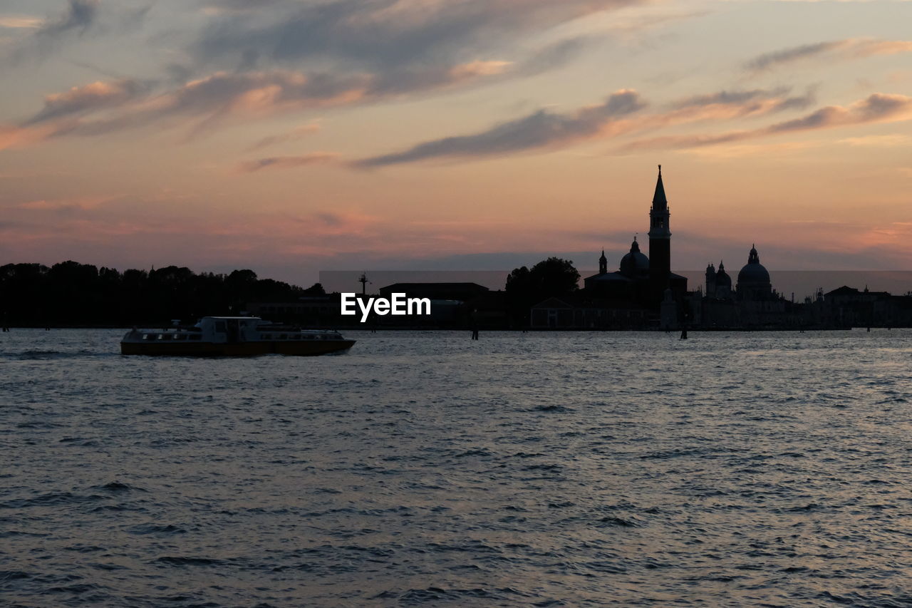 SCENIC VIEW OF RIVER BY BUILDING AGAINST ORANGE SKY