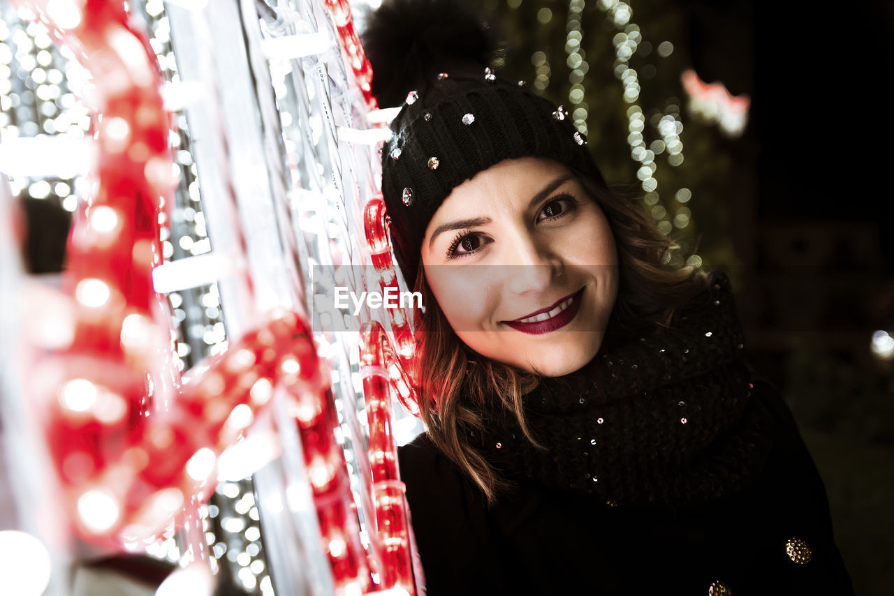 A young girl is smiling and looking at the camera with christmas light