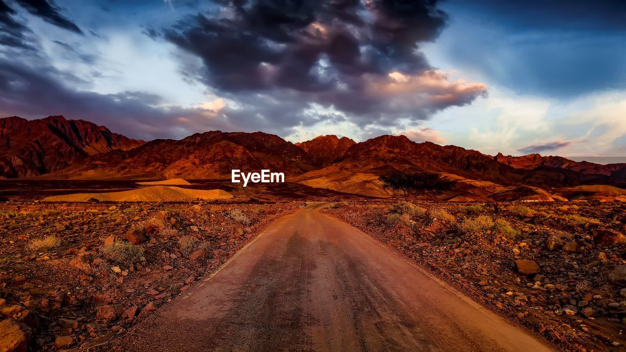 Scenic view of road through desert at sunset