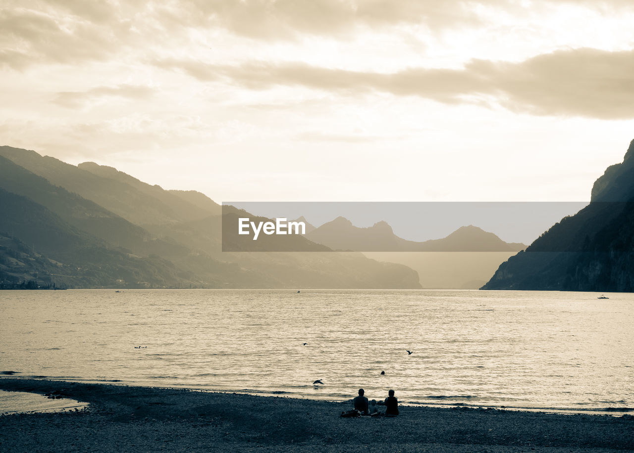 SCENIC VIEW OF SEA AGAINST MOUNTAINS