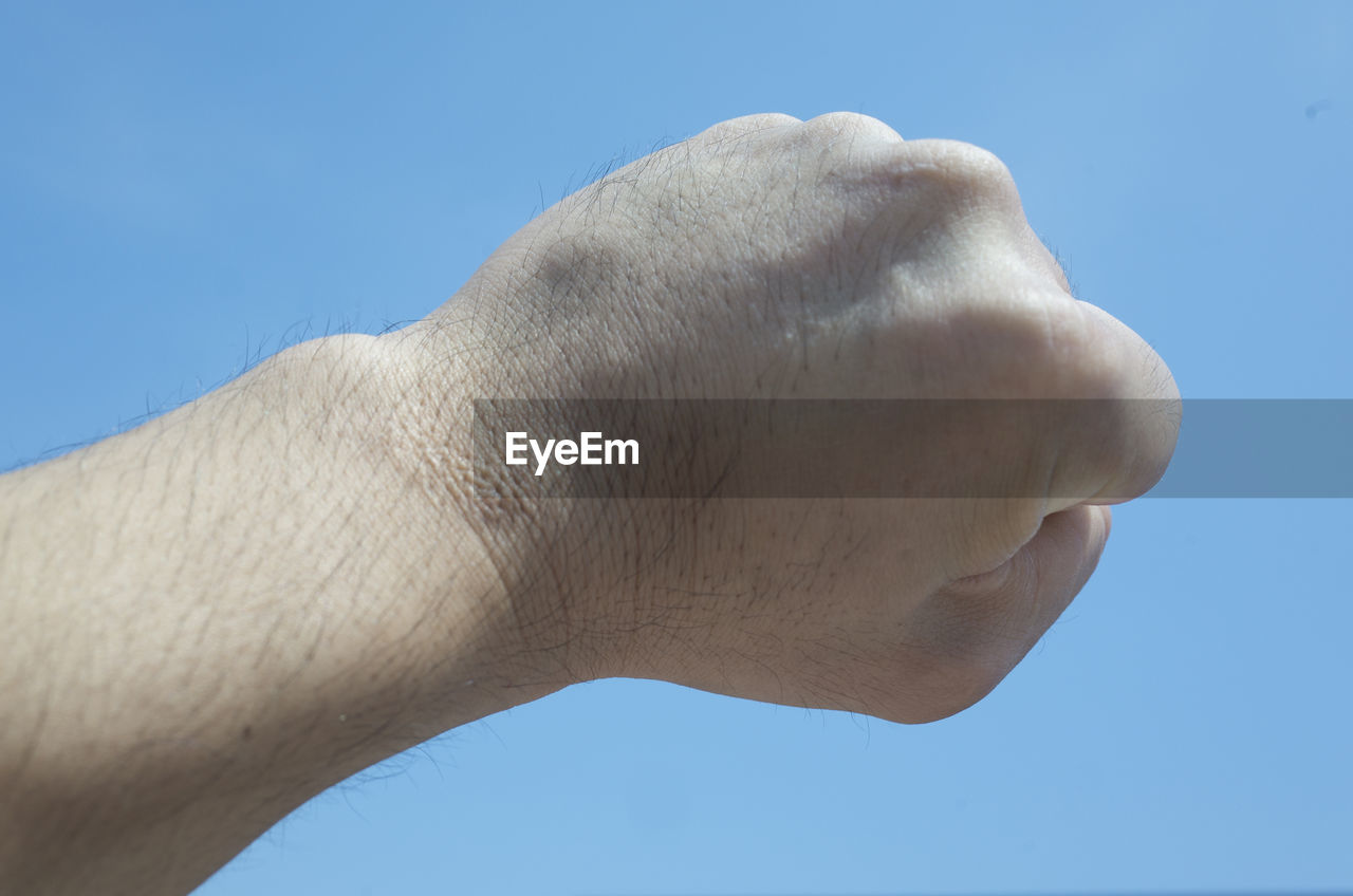 LOW ANGLE VIEW OF HUMAN HAND AGAINST CLEAR BLUE SKY