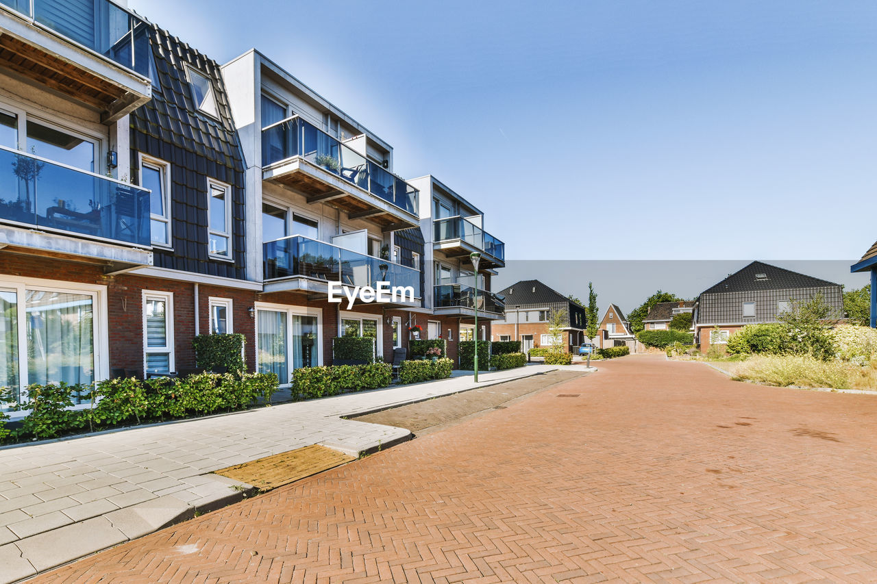 street amidst houses against clear blue sky