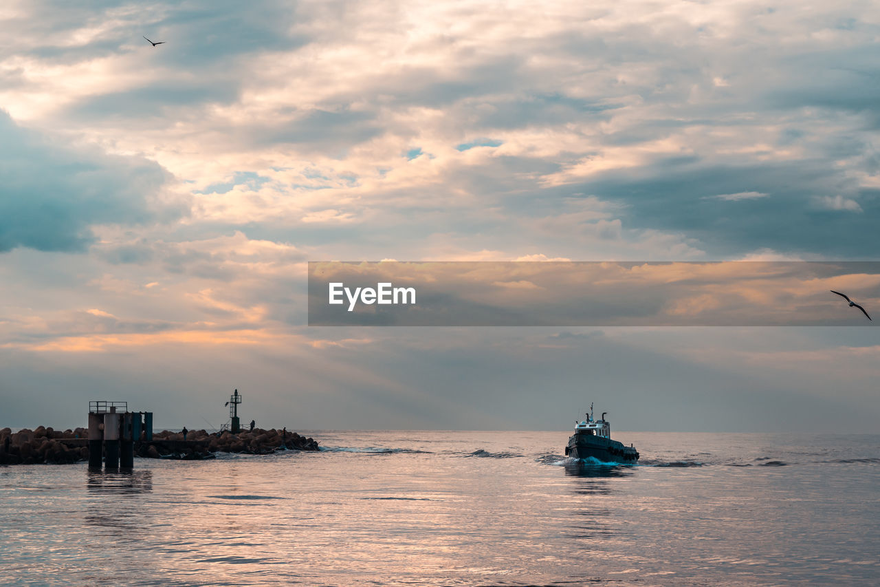 Boat sailing in sea against sky during sunset