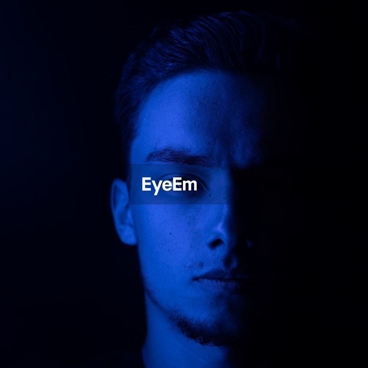 Portrait of man standing against black background