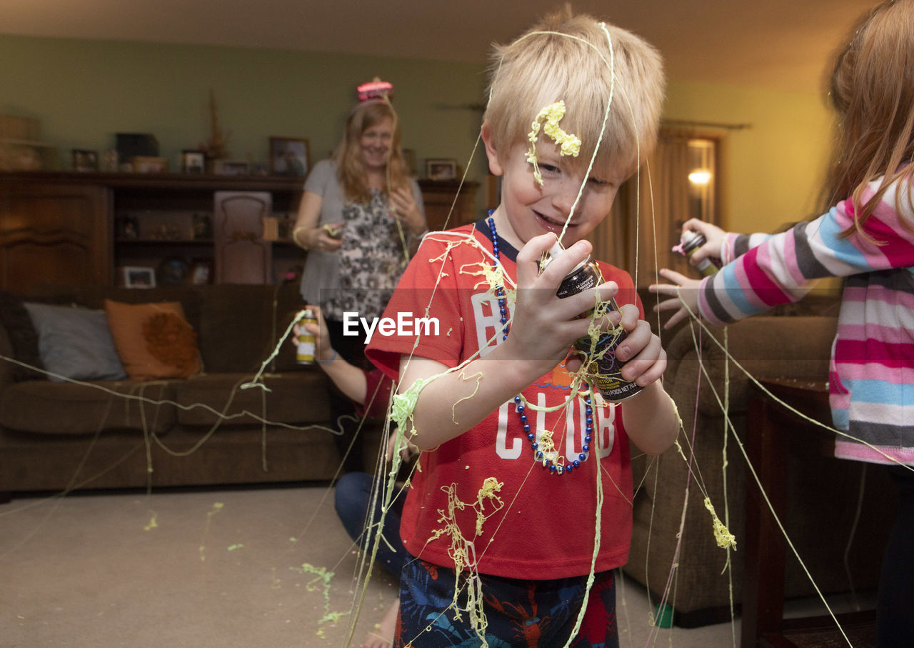 Boy holding party spray during celebration in living room at home 