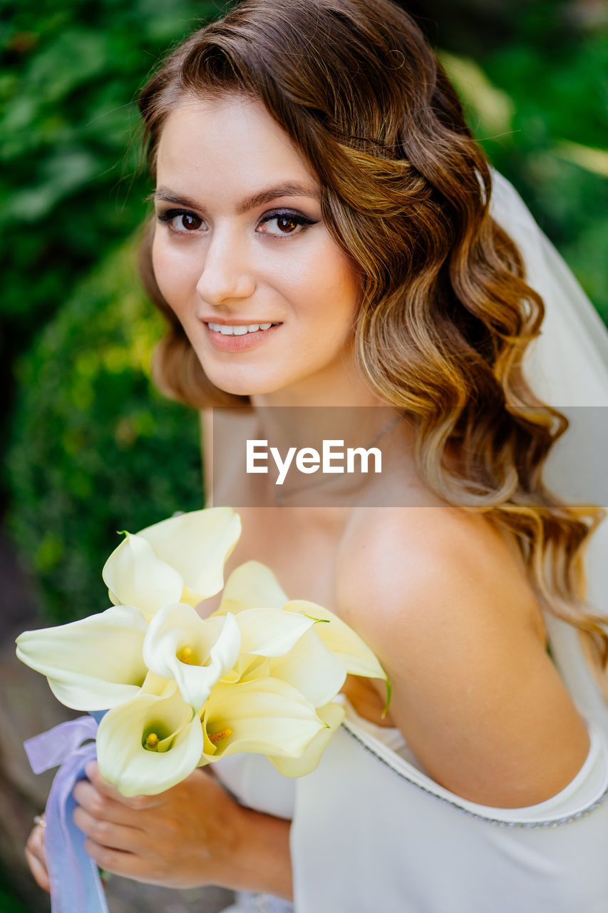 PORTRAIT OF BEAUTIFUL YOUNG WOMAN WITH RED FLOWER IN MOUTH