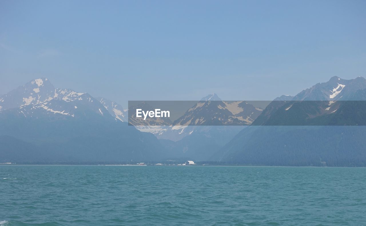 SCENIC VIEW OF SEA AND SNOWCAPPED MOUNTAINS AGAINST BLUE SKY