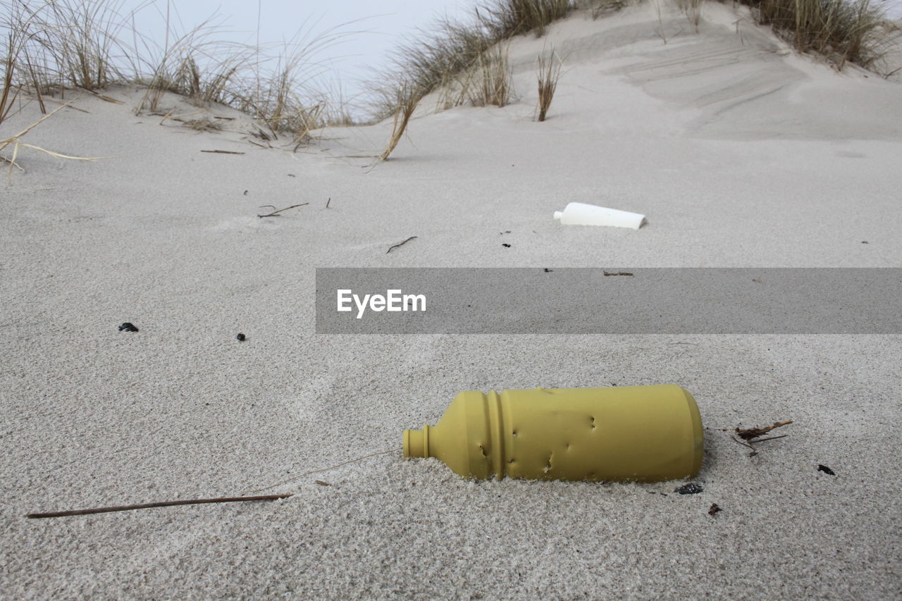 High angle view of abandoned yellow bottle on sand