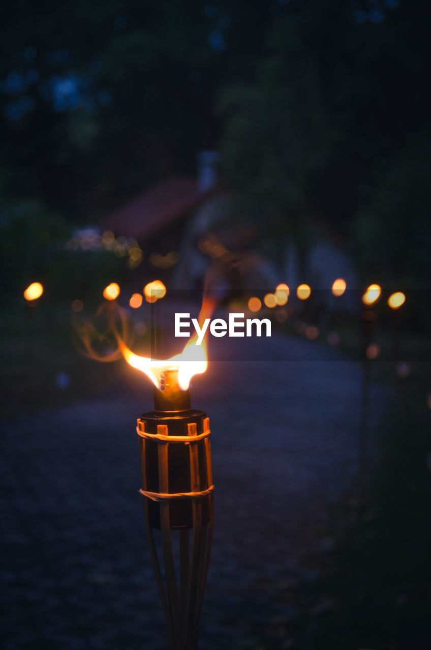 Close-up of lit torch on footpath at dusk