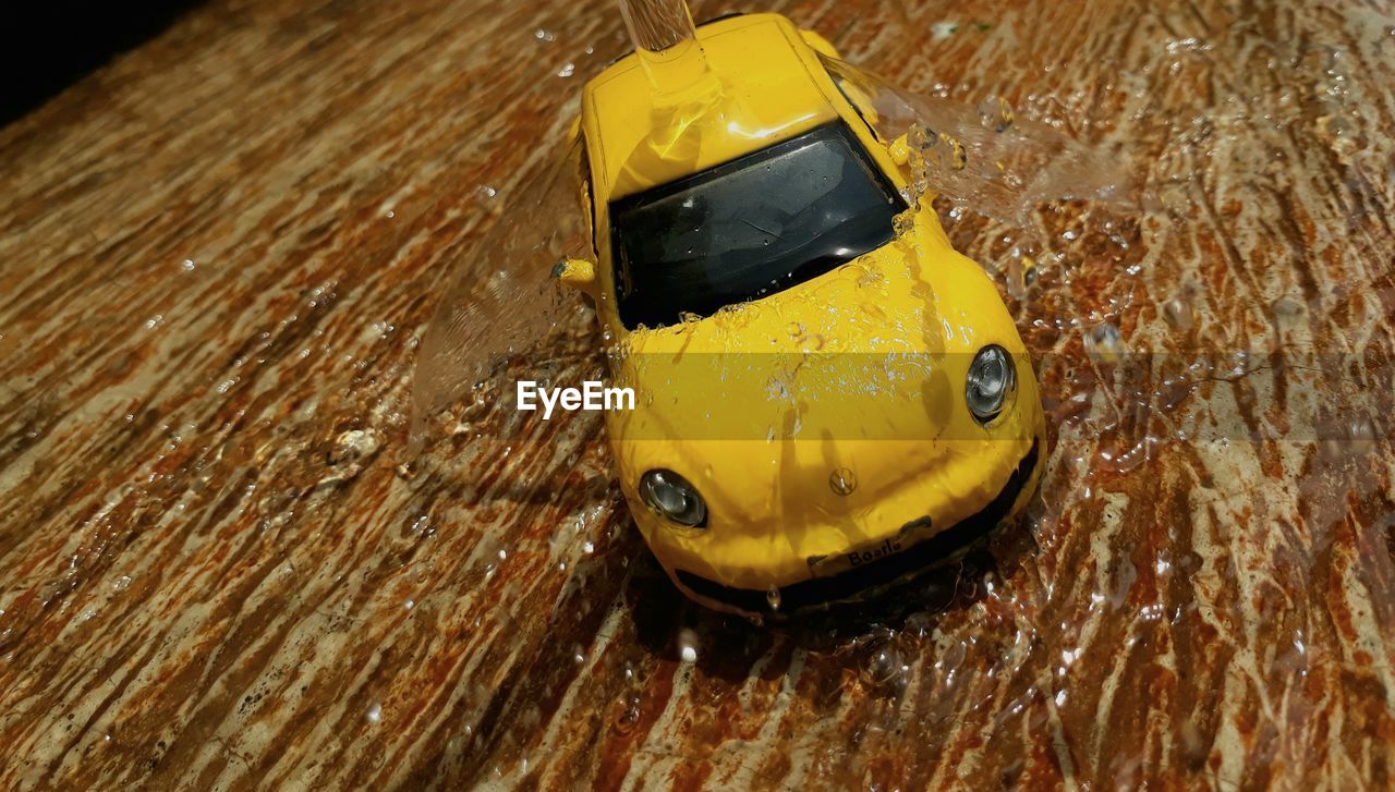 HIGH ANGLE VIEW OF YELLOW TOY IN CAR