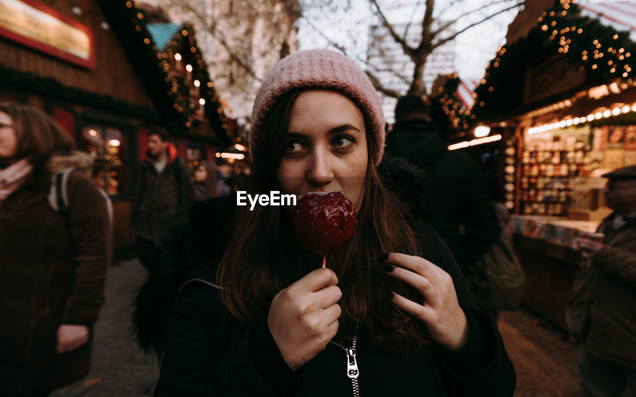 Portrait of woman holding candy apple in christmas market