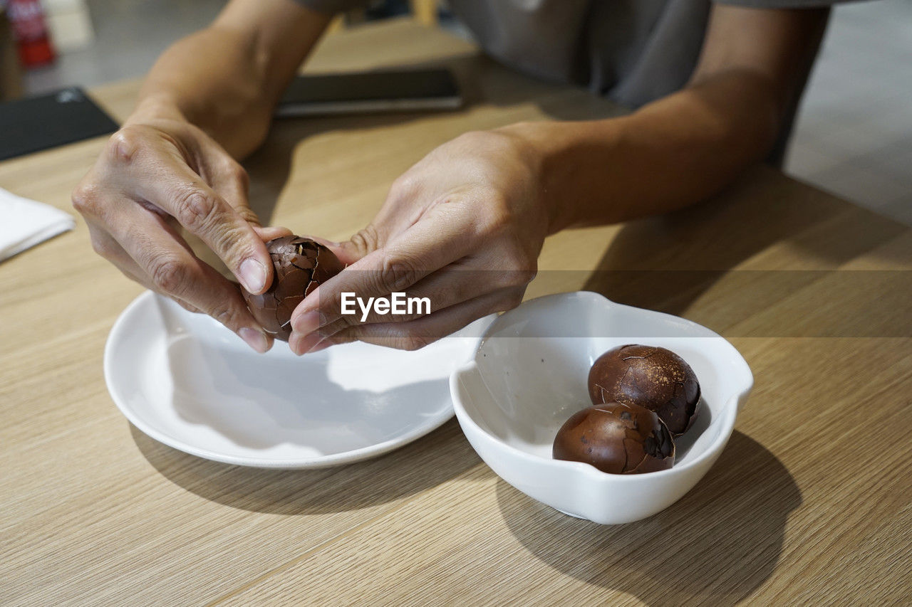 Man's hand peeling a tea infused egg at a tea house in kuala lumpur, malaysia