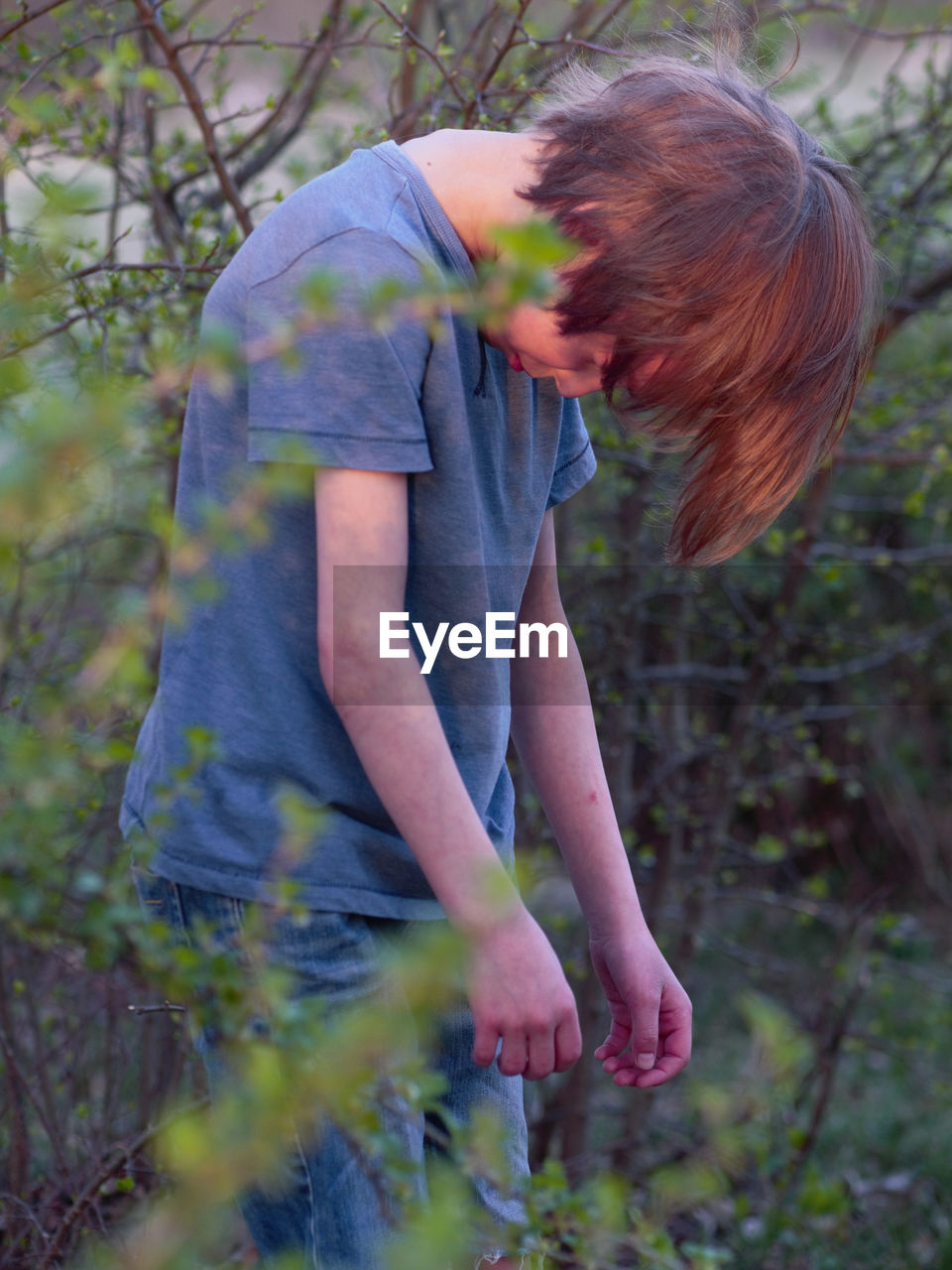 Boy looking down while standing by plants