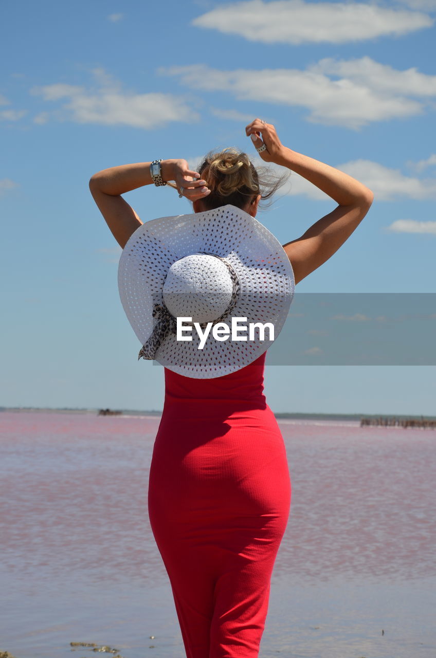 Woman standing at beach against sky