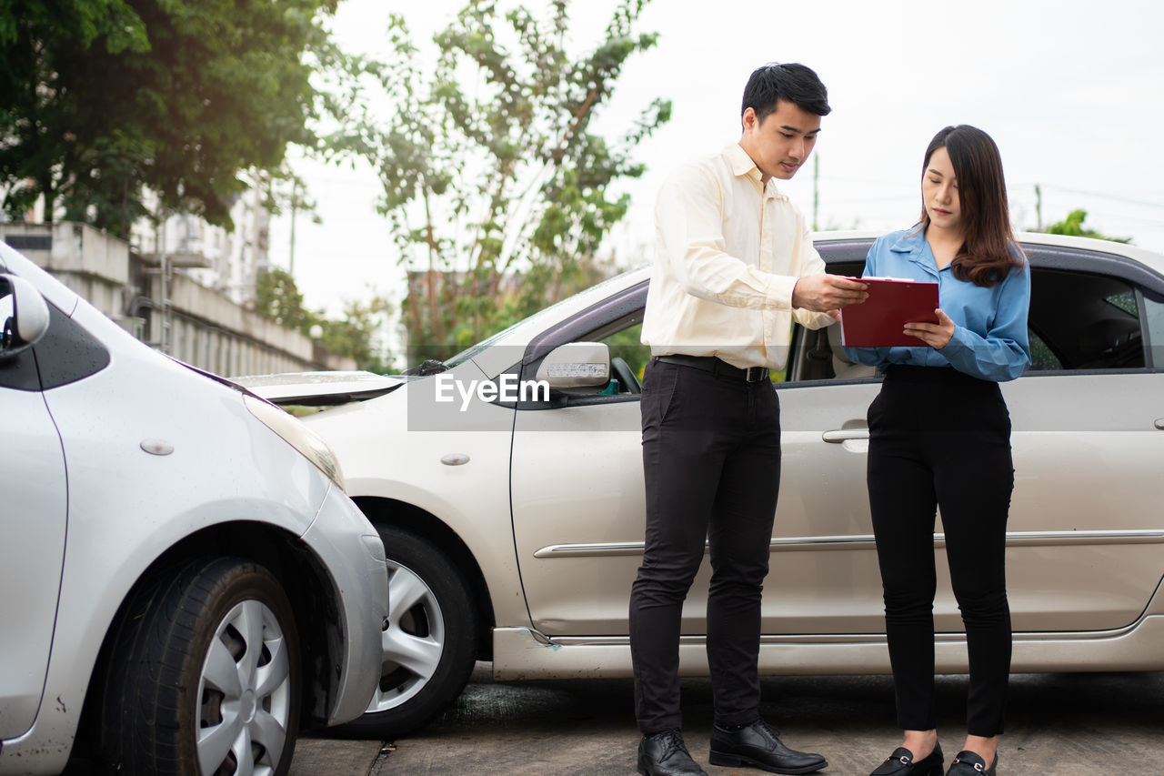 Asian women driver talk to insurance agent for examining damaged car and customer checking