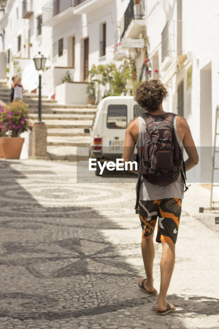 Rear view of man walking on street by buildings