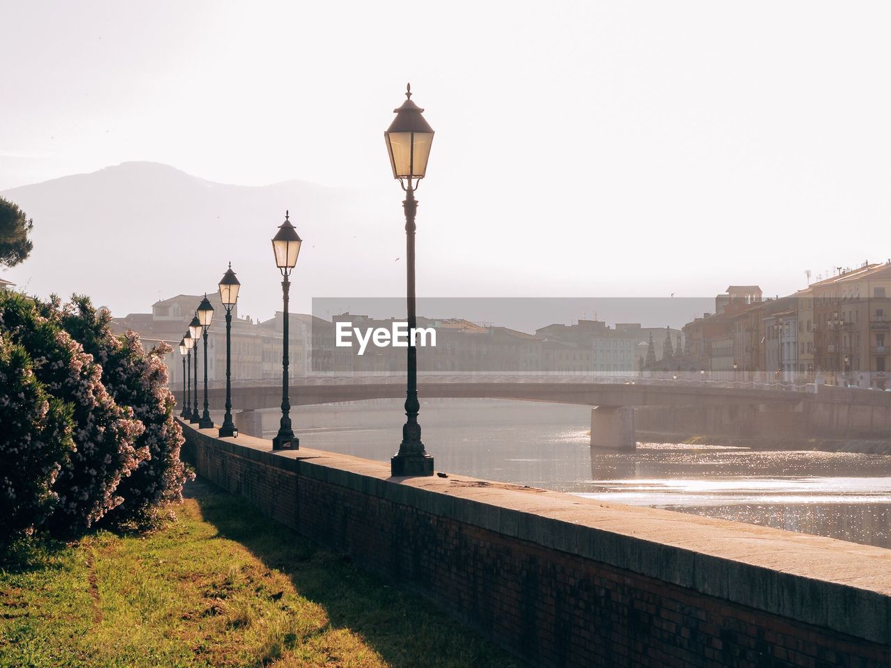 Street light by river in city against clear sky