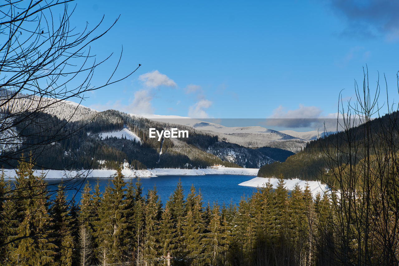 Scenic view of lake by snowcapped mountains against sky