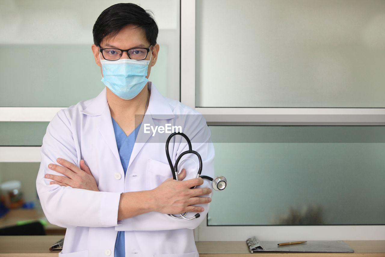 FULL LENGTH OF MAN WEARING MASK STANDING IN FRONT OF WALL