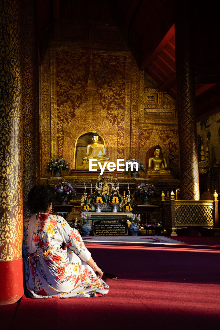 REAR VIEW OF A BUDDHA STATUE AGAINST TEMPLE