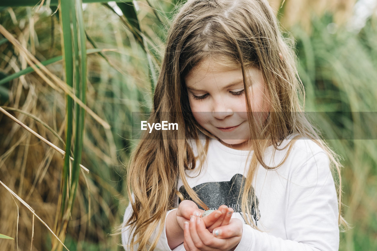 Young girl holding a small birds egg in her hands