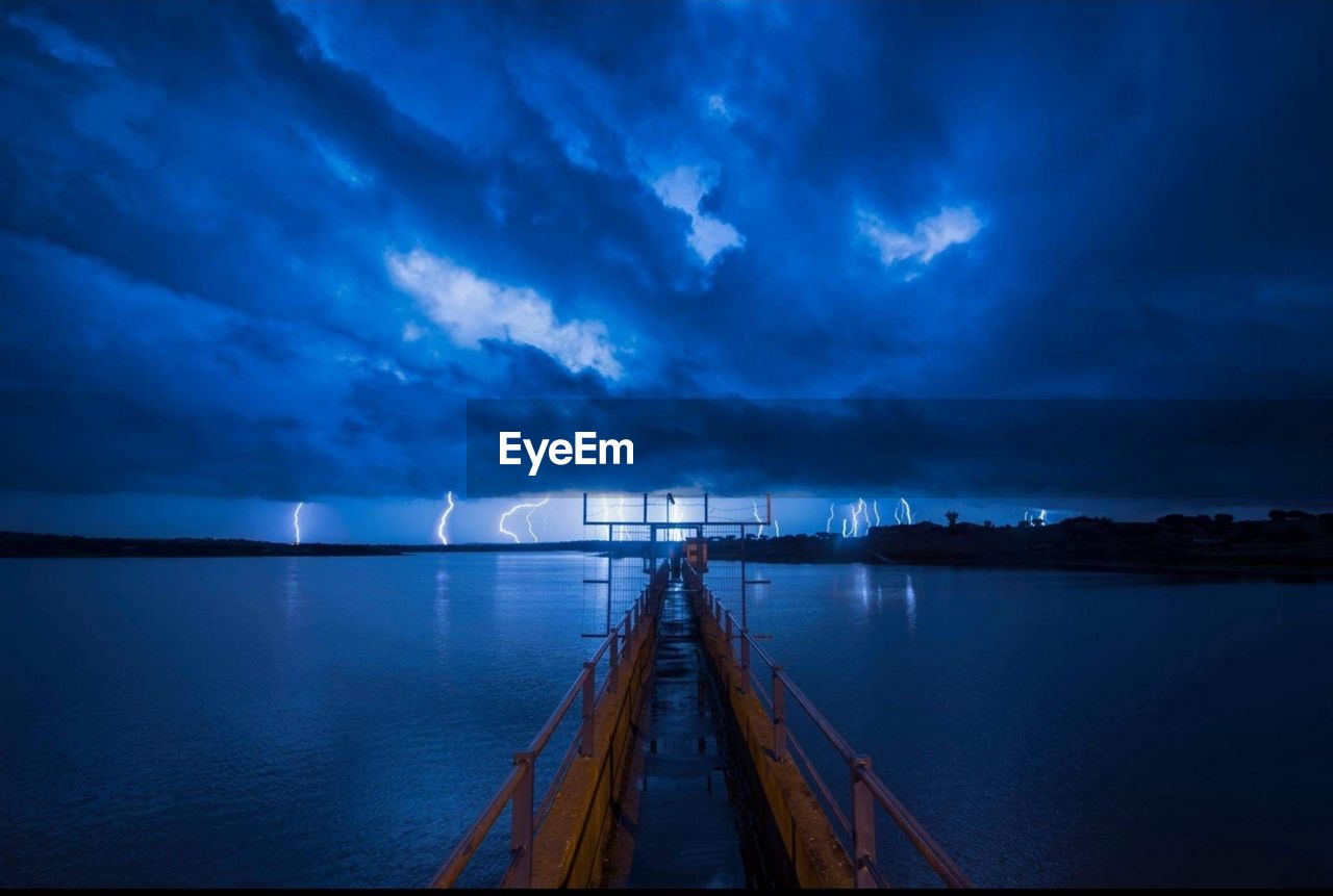 Scenic view of sea against cloudy sky at night