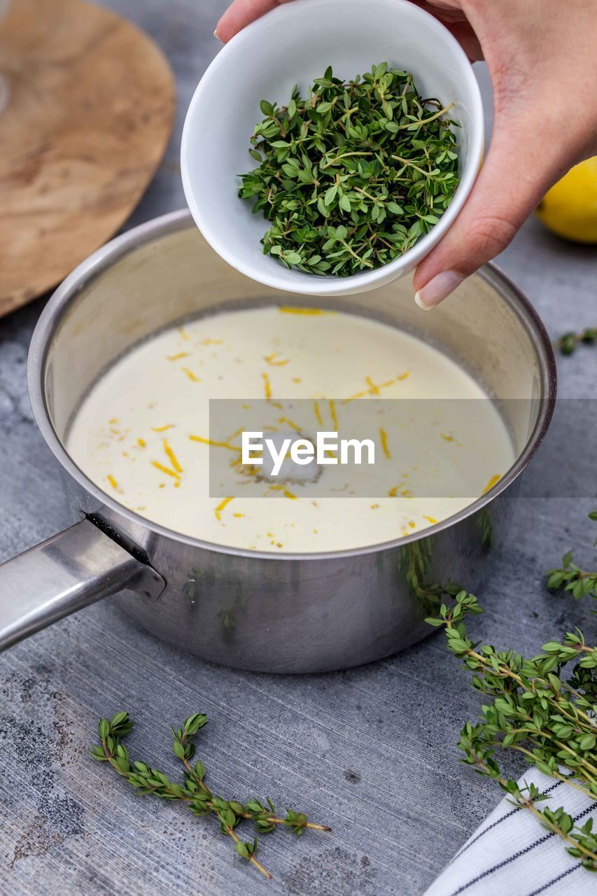 Cropped image of hand putting herb in cream