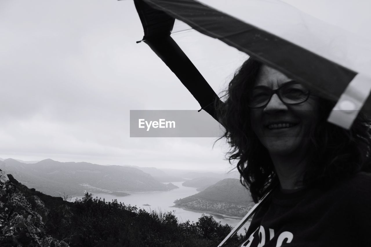 Portrait of smiling young woman against sky