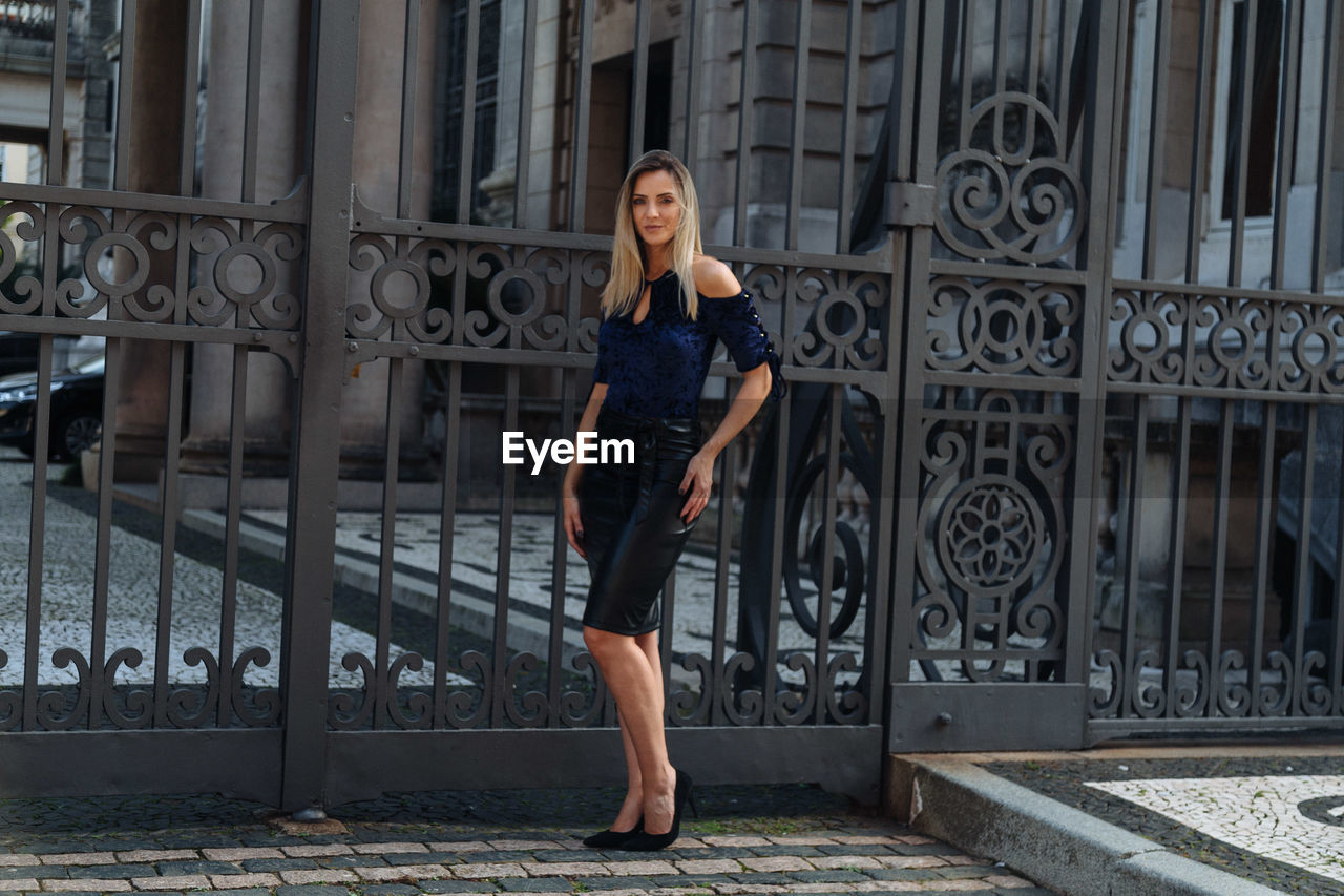 Portrait of woman standing against metal gate