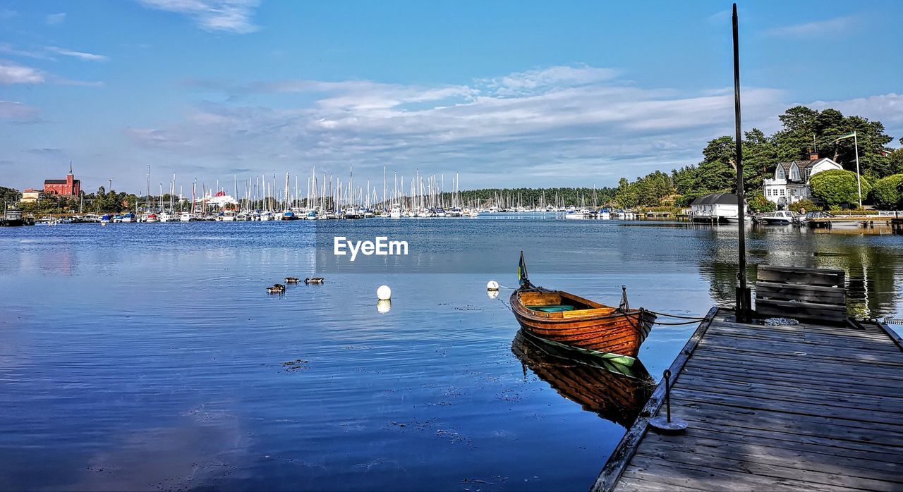 Sailboats moored in sea against sky