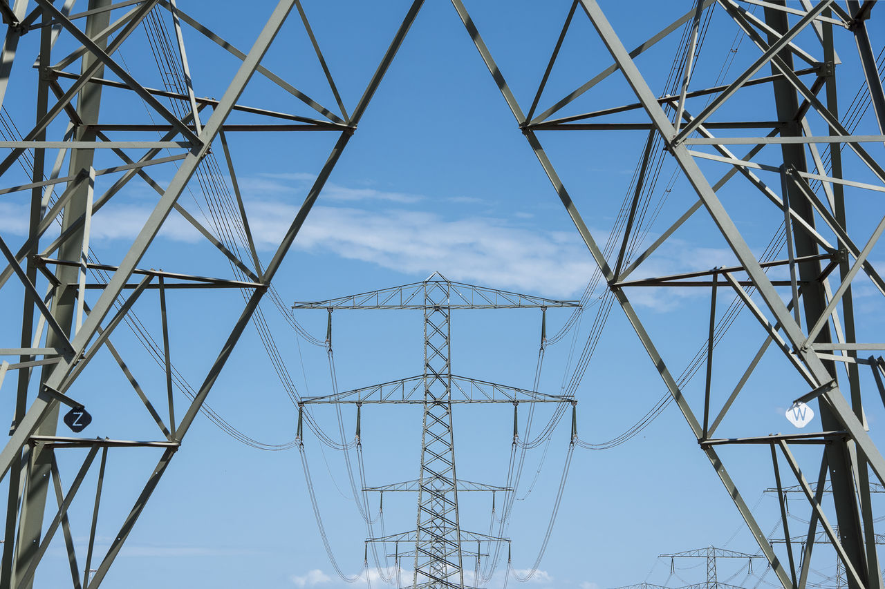 Electricity mast and transmission towers on the background on a blue sky