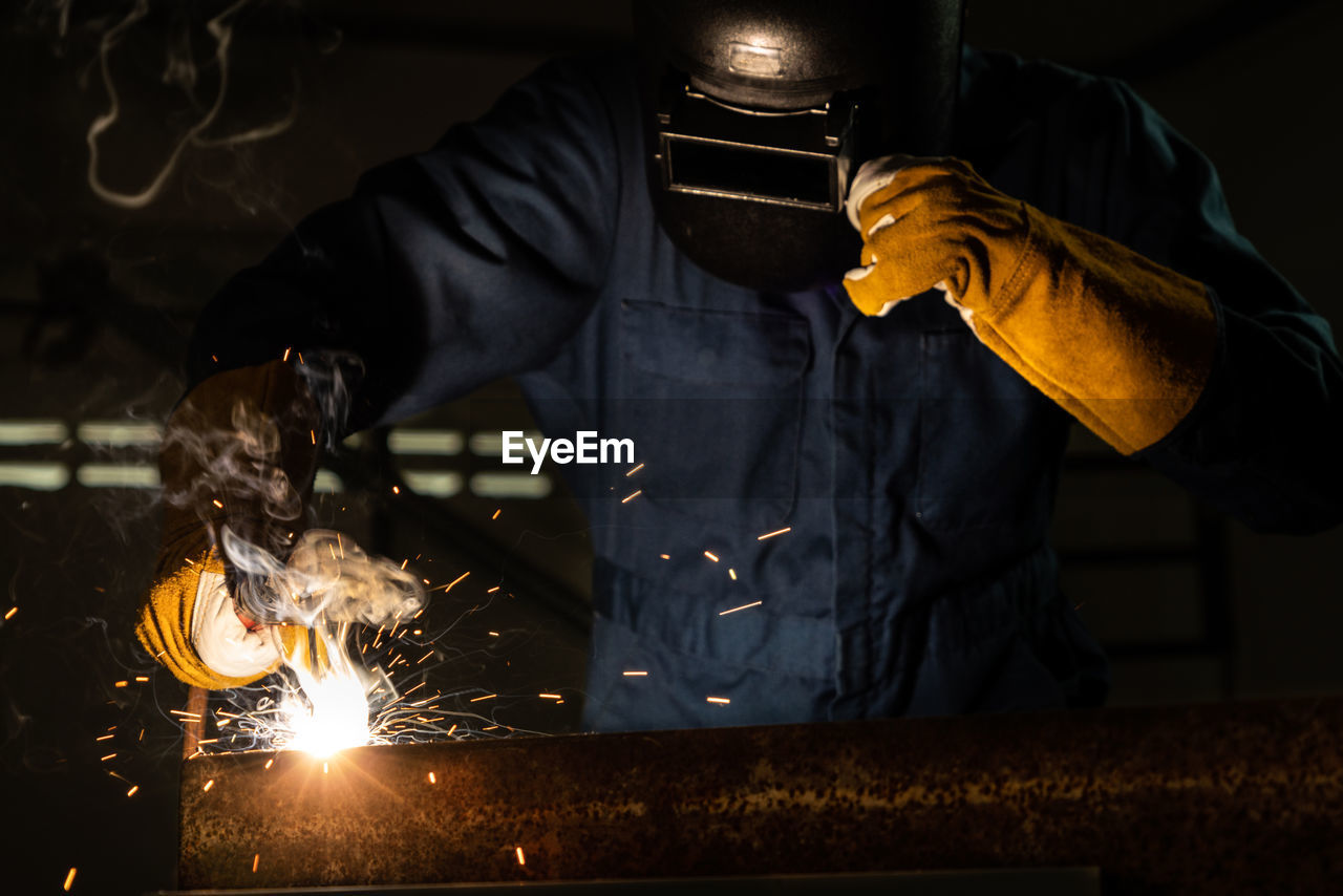 MIDSECTION OF MAN WORKING ON METAL