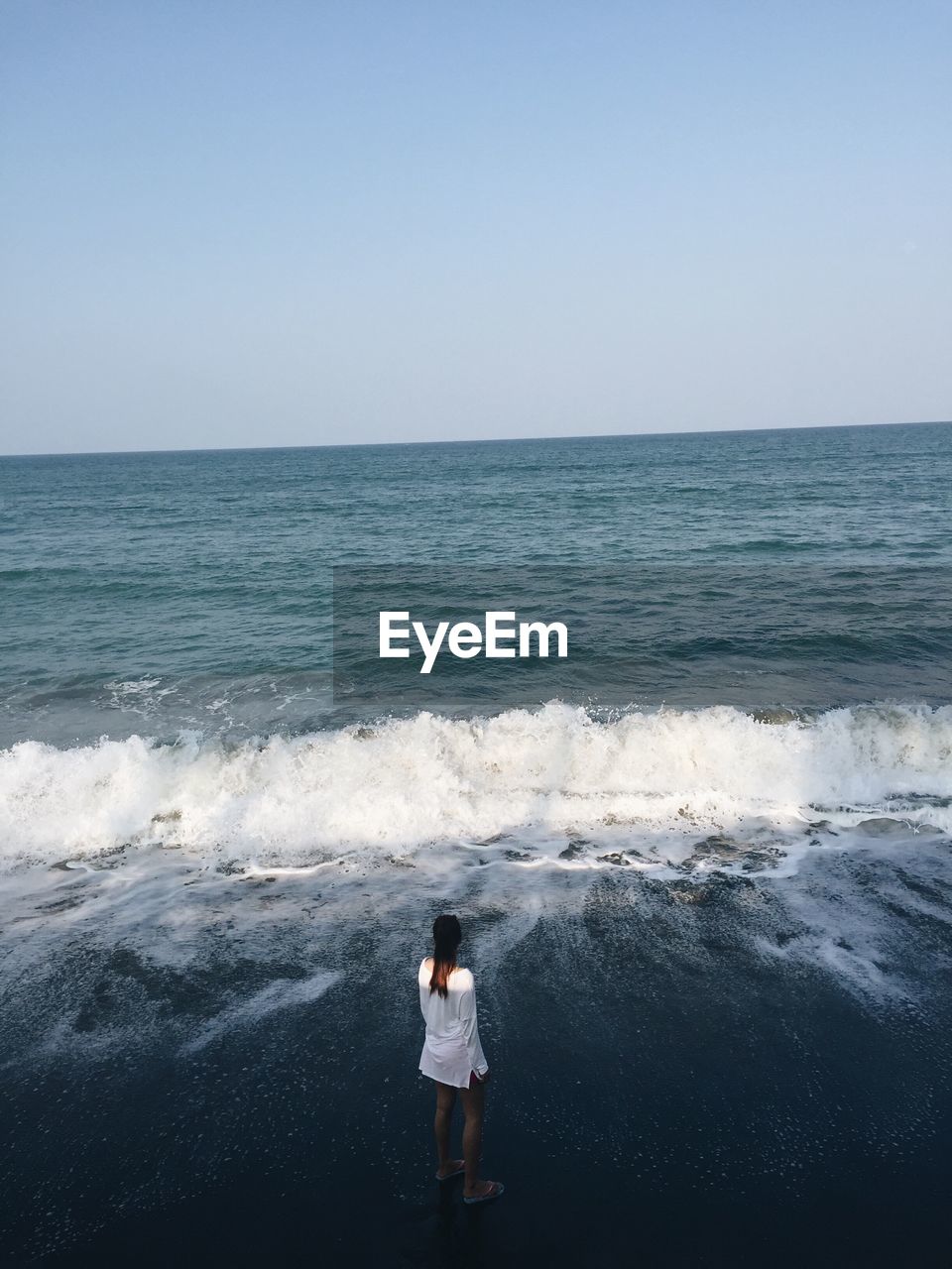 Rear view of woman standing on shore at beach