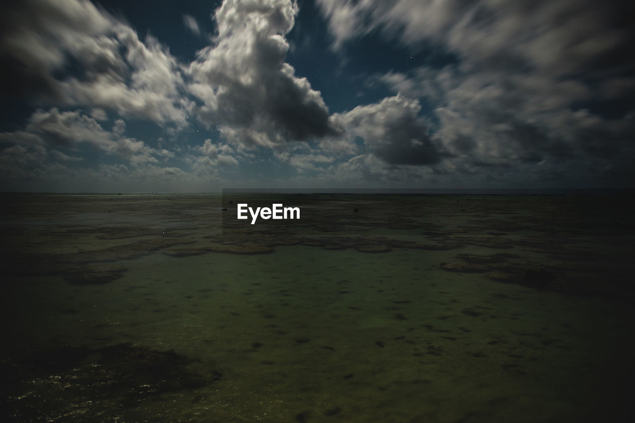 SCENIC VIEW OF BEACH AGAINST STORM CLOUDS