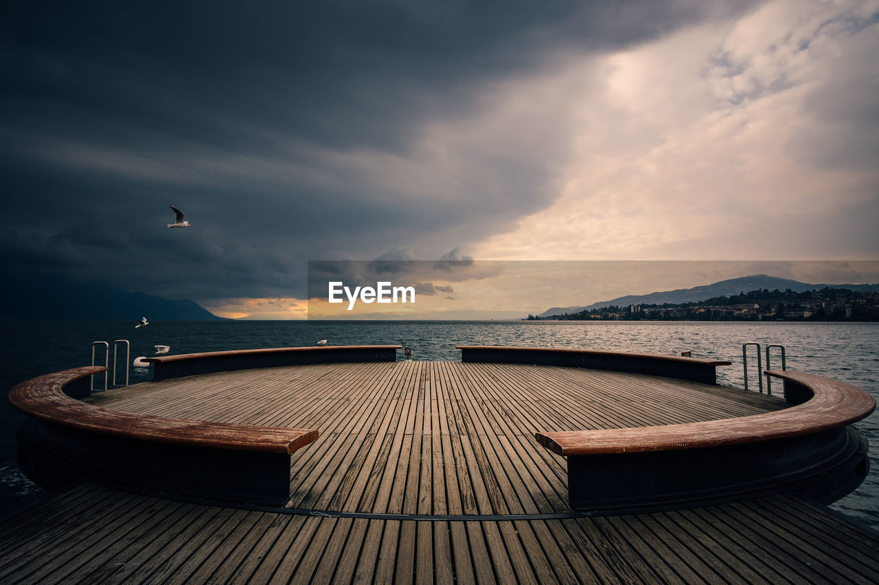 Empty pier over sea against sky at sunset