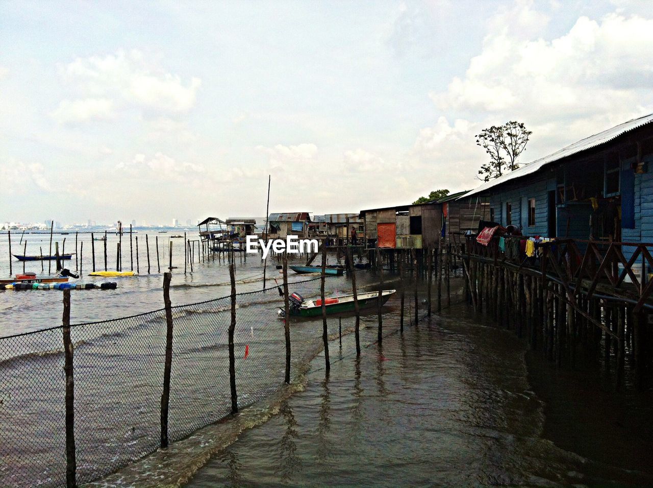 Wooden houses and boats at shore against sky