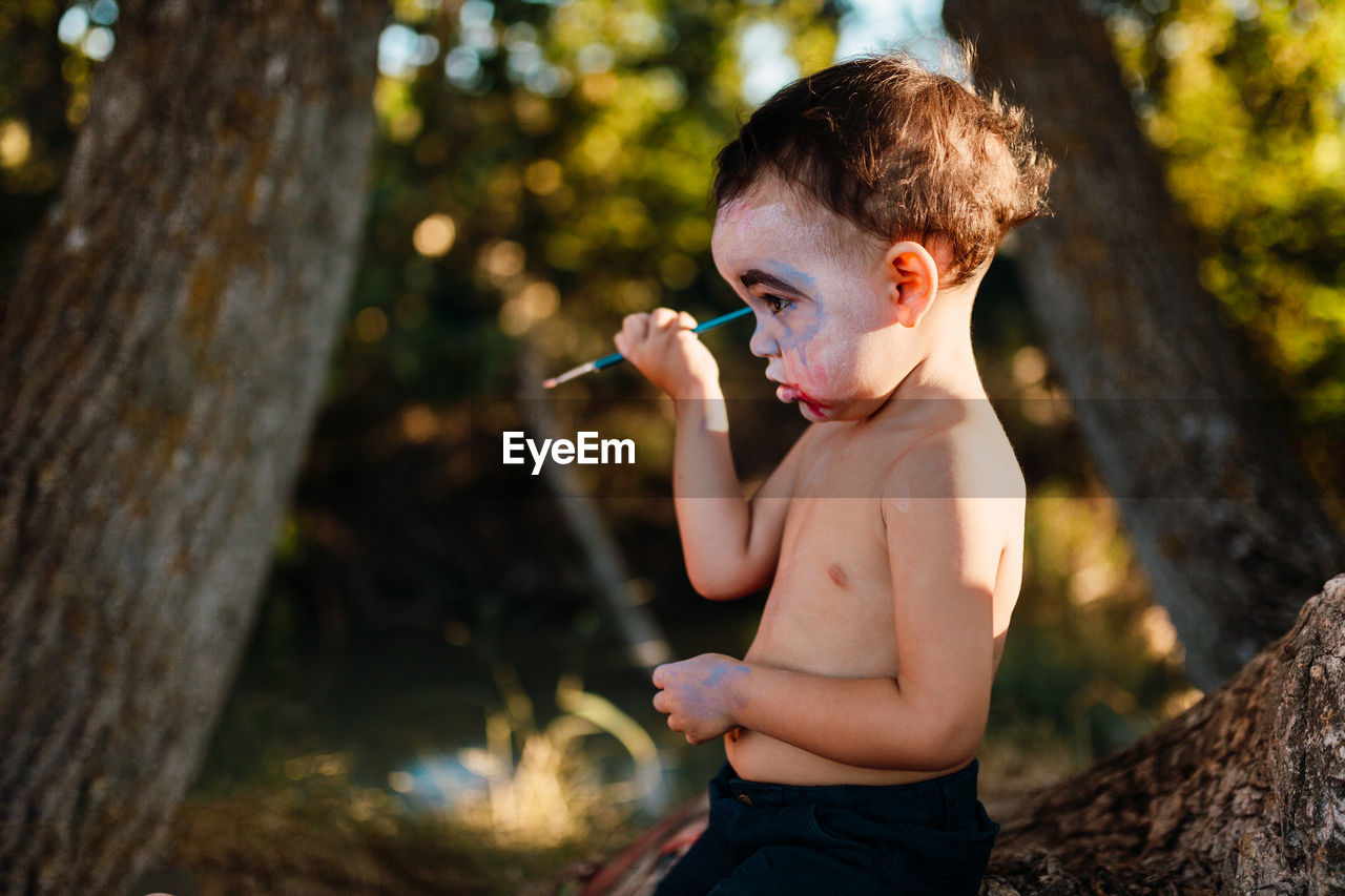 FULL LENGTH OF SHIRTLESS BOY HOLDING LEAF