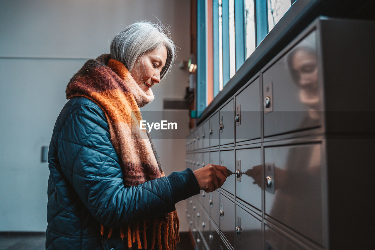 Side view of woman locking locker