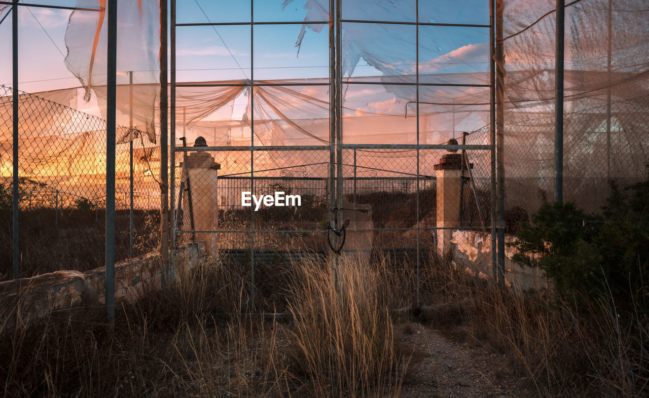 sky, architecture, sunset, nature, plant, urban area, built structure, reflection, outdoors, tree, evening, sunlight, no people, building exterior, fence, grass, landscape, cloud, land, building